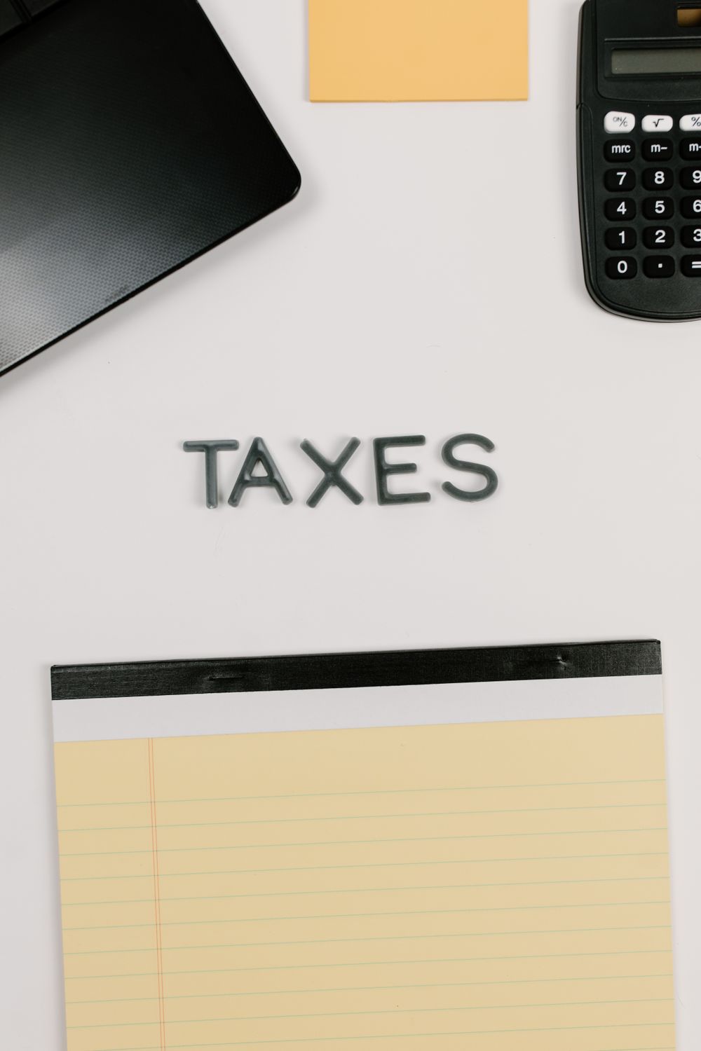 Kalkulator, notatnik i napis taxes na jasnym biurku – symbol rozliczeń podatkowych
