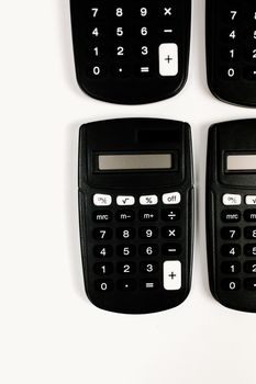 Simple black calculators arranged on white background, representing finance and calculation concepts.