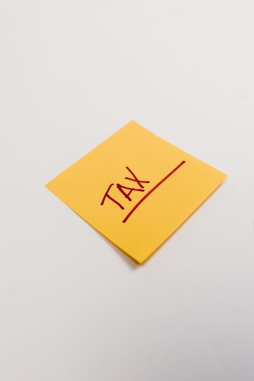 Free Yellow sticky note on white background with the word 'Tax' in red ink, ideal for finance concepts. Stock Photo