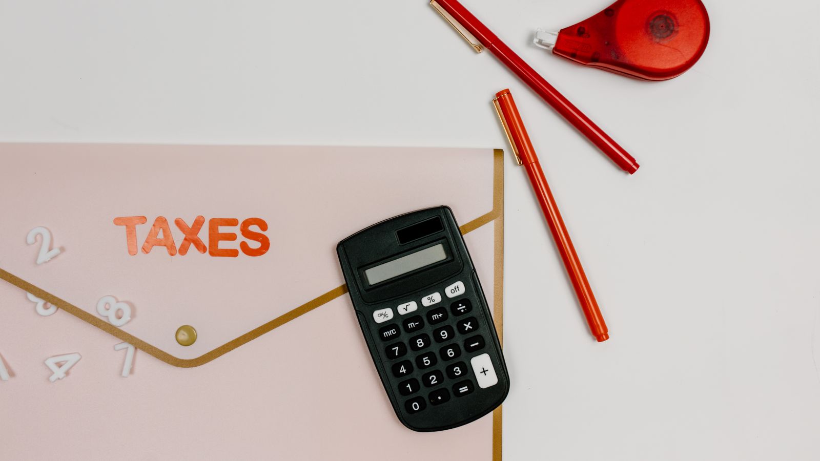 Flat lay image featuring a calculator, pens, and a folder labeled 'TAXES', perfect for finance-related themes.