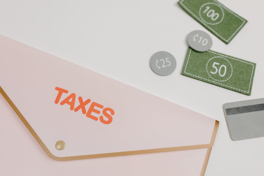 An image of an envelope with the name taxes surrounded by play money and debit card to show the importance of how to register as a freelancer on BIR