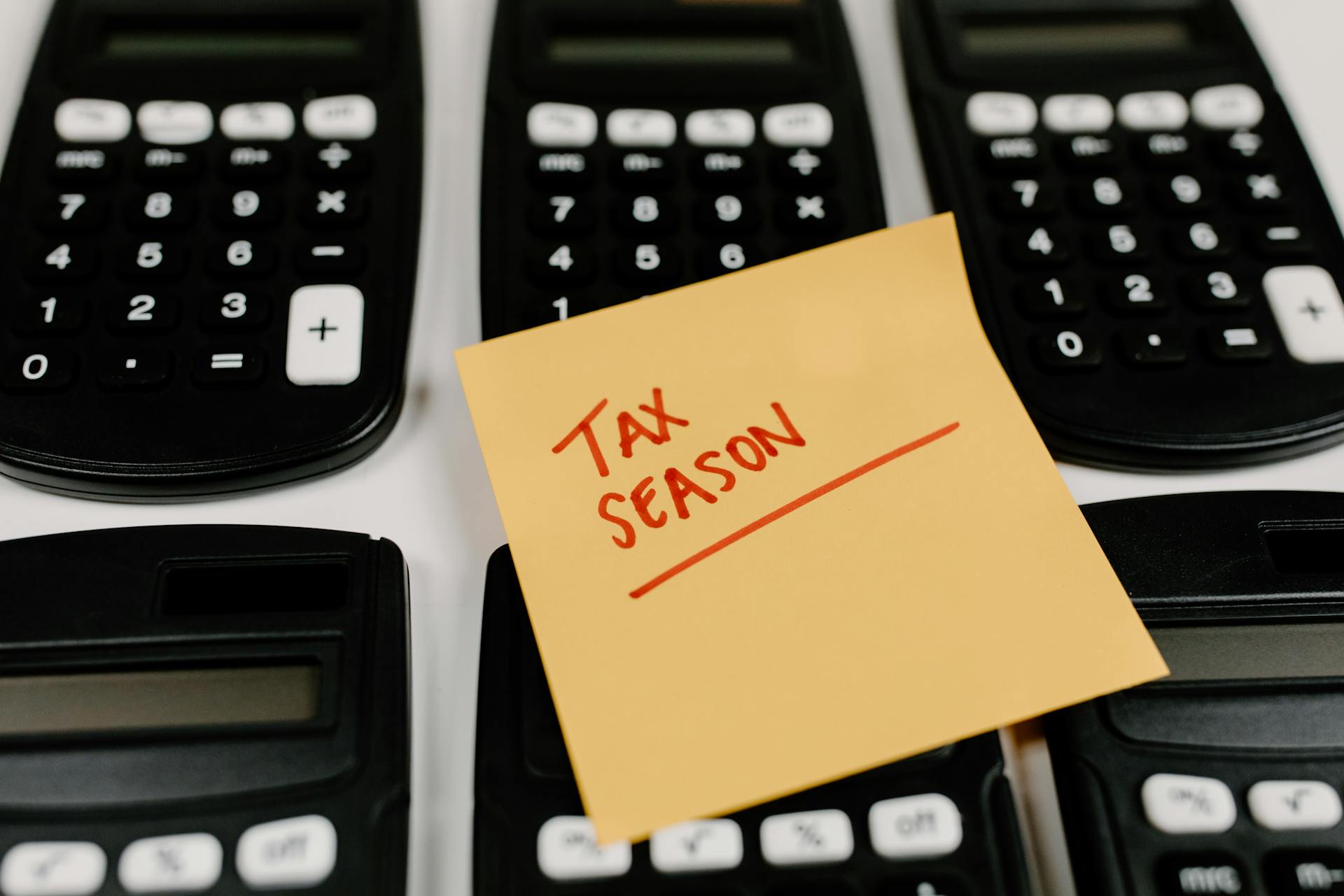 Close-up of calculators and a sticky note labeled 'Tax Season', symbolizing tax preparation.