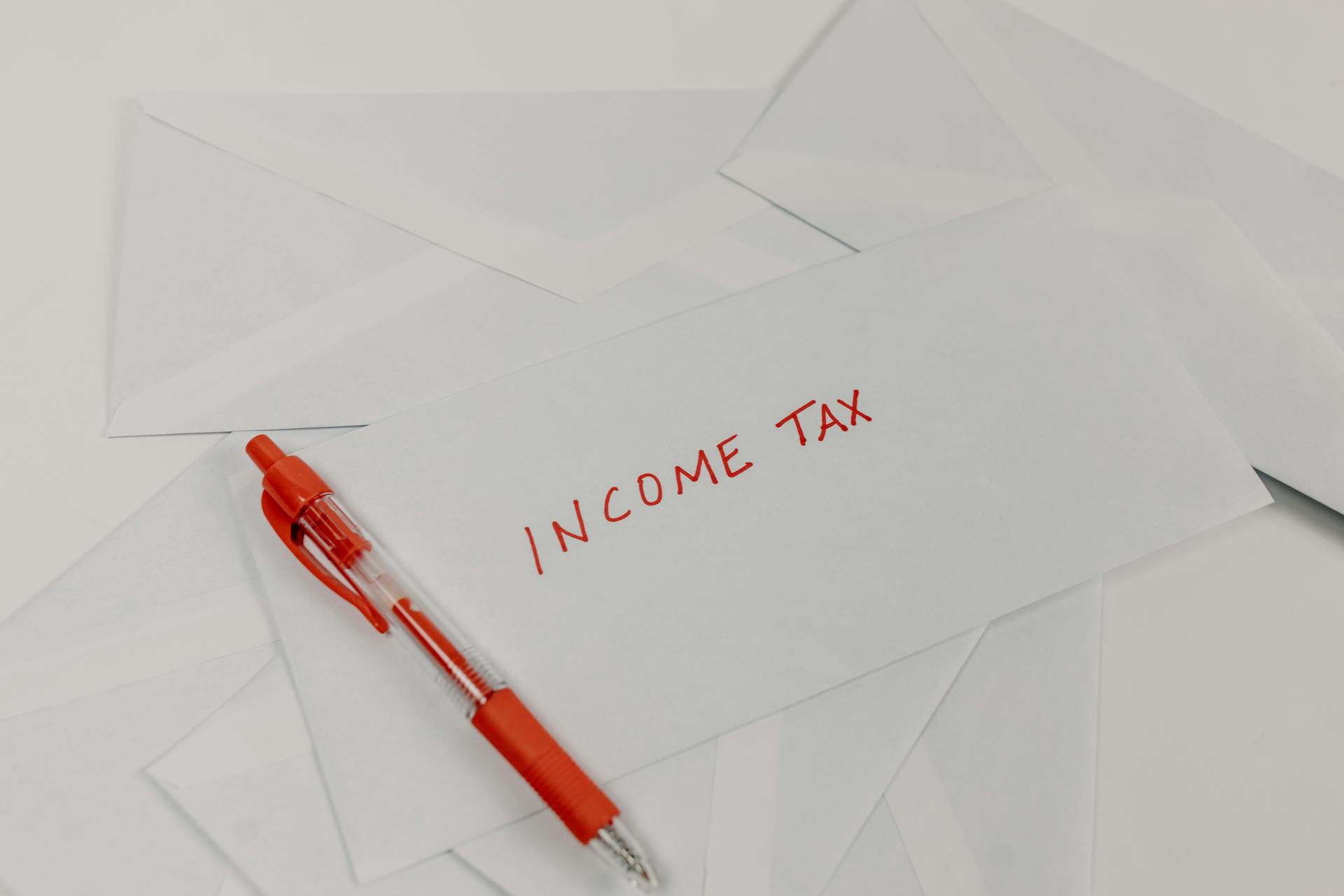 Studio shot of income tax envelope with red pen for accounting and tax season preparation.