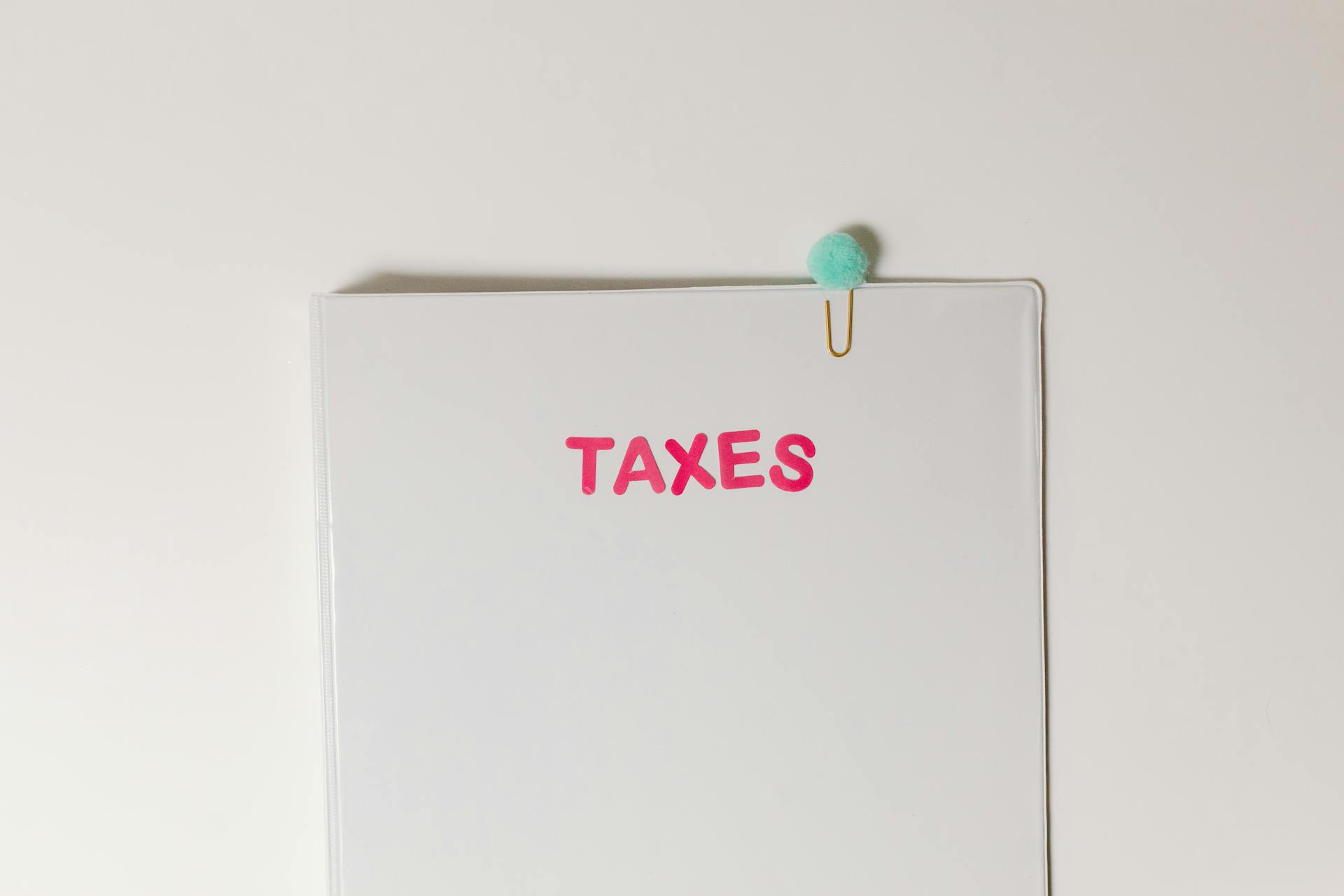 Close-up of a tax file with a pink 'TAXES' label and a paperclip, offering copy space and a conceptual minimalist design.