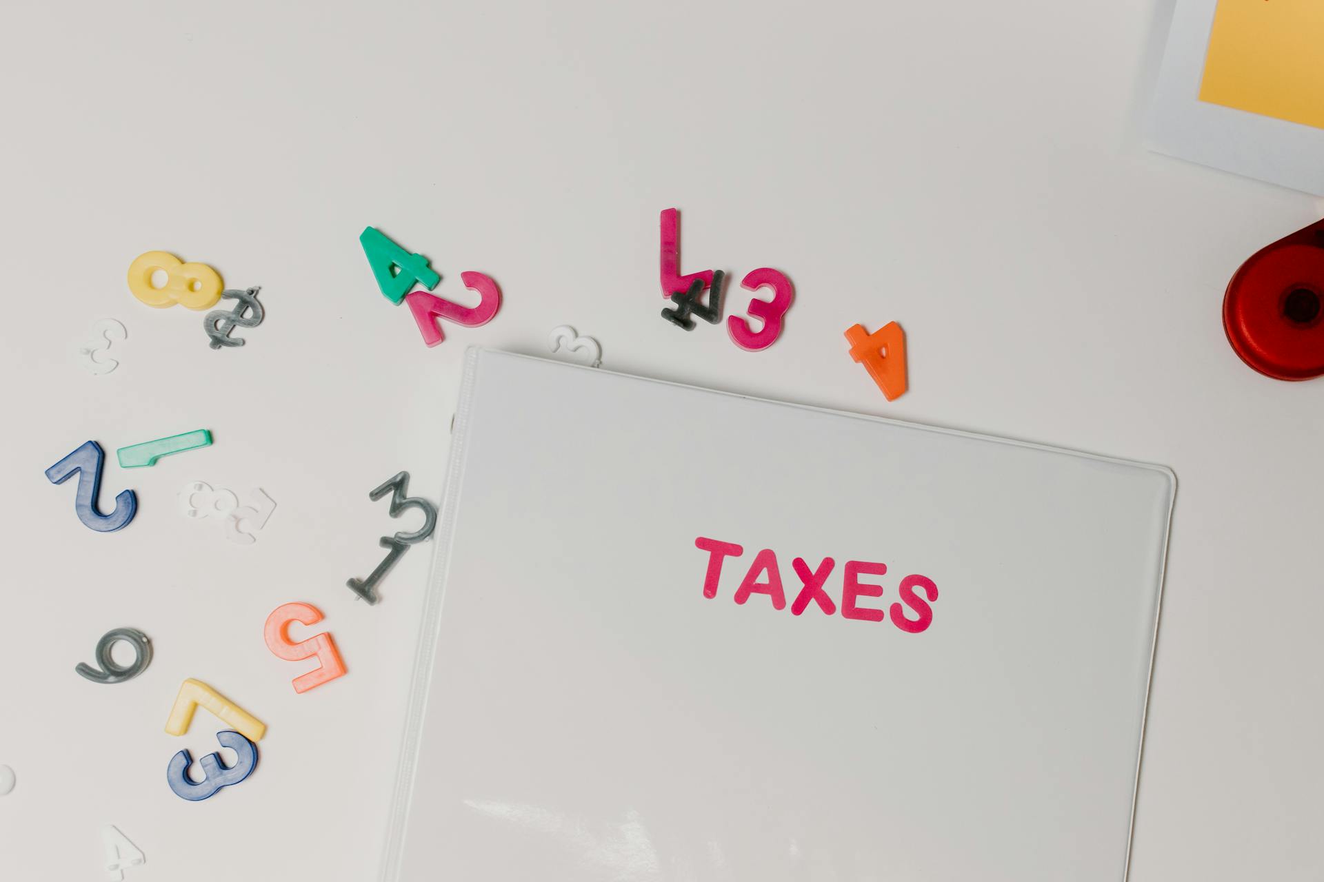 Colorful magnetic numbers scattered around a file labeled 'TAXES', symbolizing financial organization.