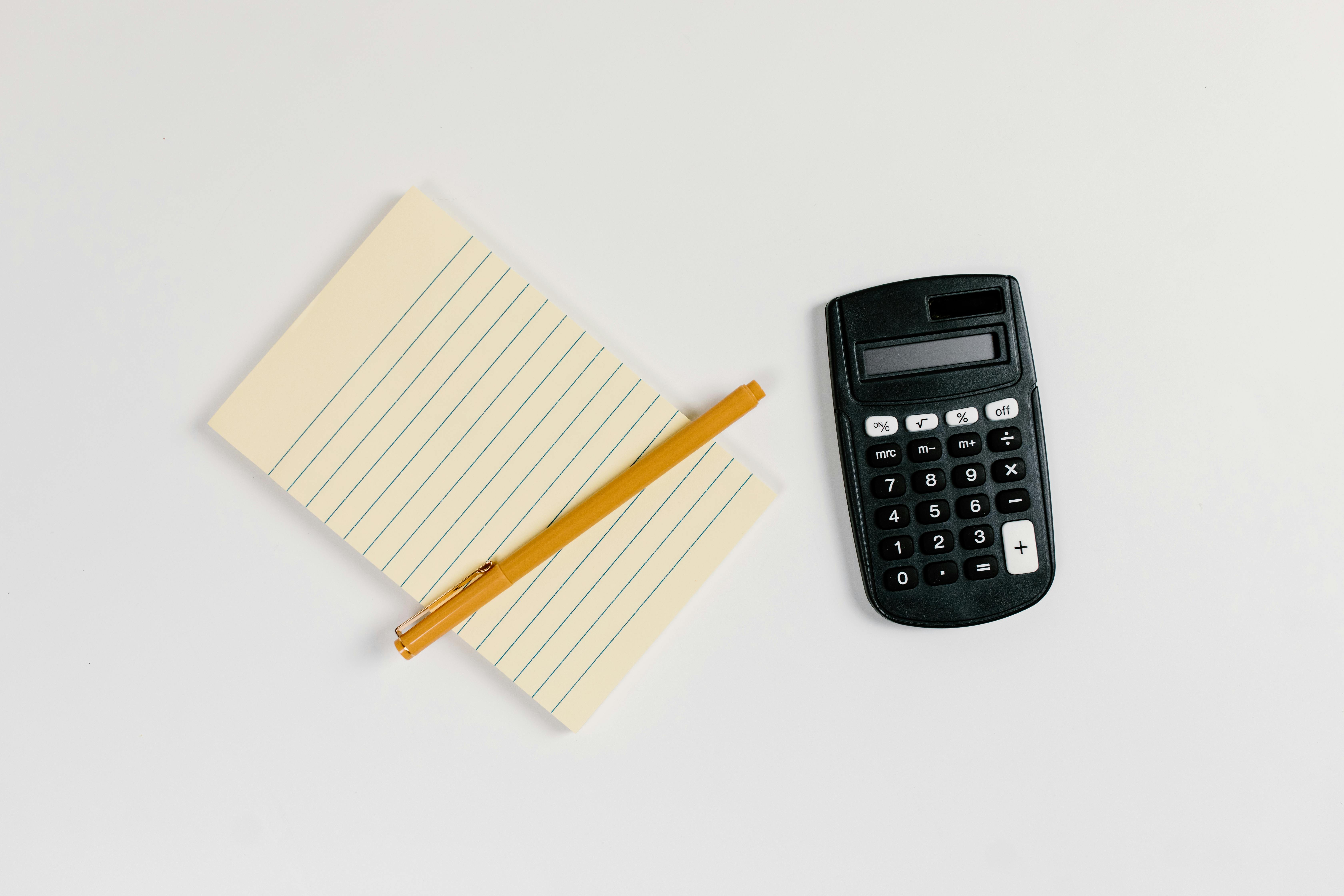 close up shot of a black calculator beside a yellow paper