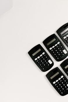 Top view of multiple black calculators arranged on a white surface for business or education use.