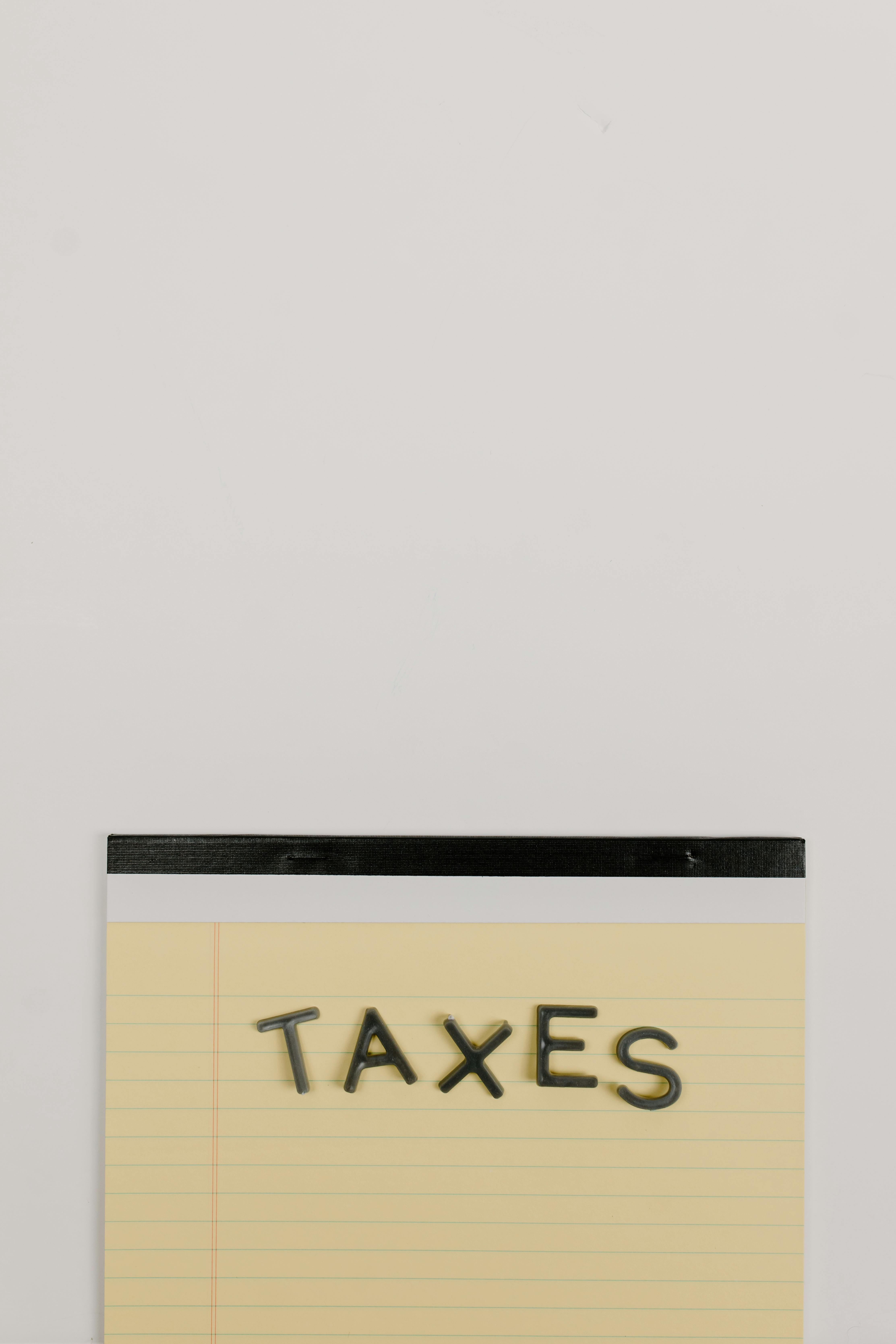 Notepad with the word 'Taxes' on a white background, ideal for finance themes.