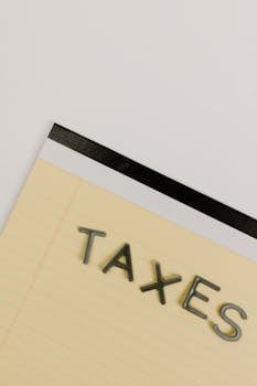 A minimalist image of a notepad displaying the word TAXES on a white background.