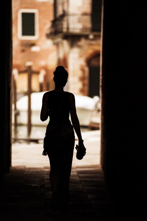 Free Silhouette of a woman walking in a Venetian alley with a canal view. Stock Photo