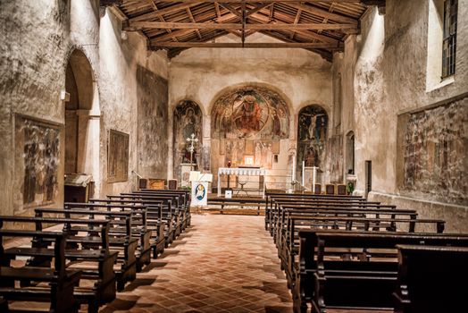 Beautifully preserved chapel interior in Sirmione, Lombardy, showcasing vintage frescoes and wooden architecture.