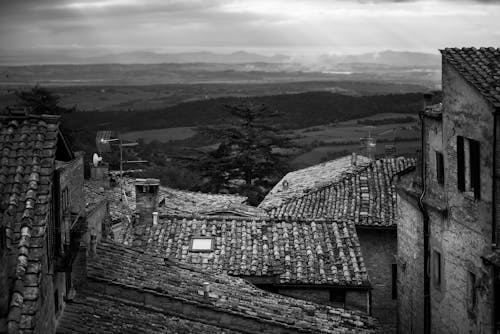 Black and White Photo of Roofs and Hills 