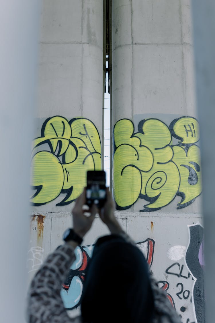 Anonymous Blogger Taking Photo Of Graffiti Wall On Smartphone