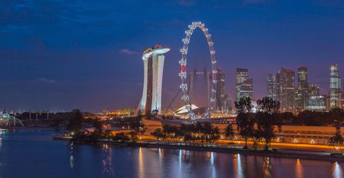 Free Stunning night view of Singapore with Marina Bay Sands and Ferris Wheel, reflecting city lights on water. Stock Photo
