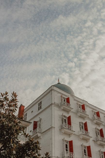 Low angle view of a historic building with red shutters and a dome, beneath cirrocumulus clouds in Istanbul.