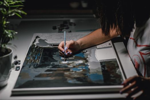 A close-up view of a person painting on a canvas, capturing artistic creativity.