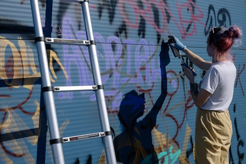 Free A Woman Doing a Graffiti on a Wall Stock Photo