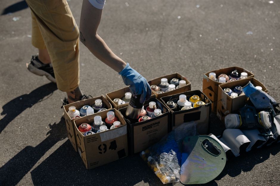 Close-up of an artist picking spray paint cans from boxes on a sunny day.