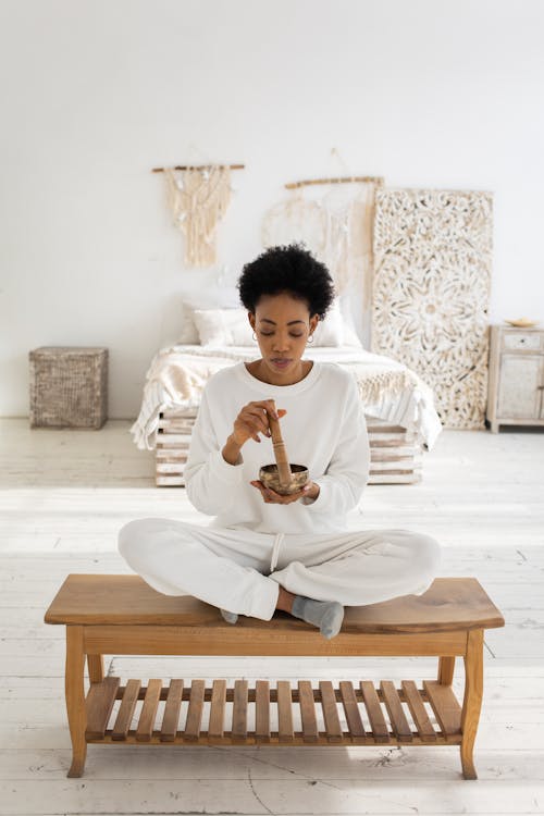 A Woman in White Long Sleeves Using a Singing Bowl