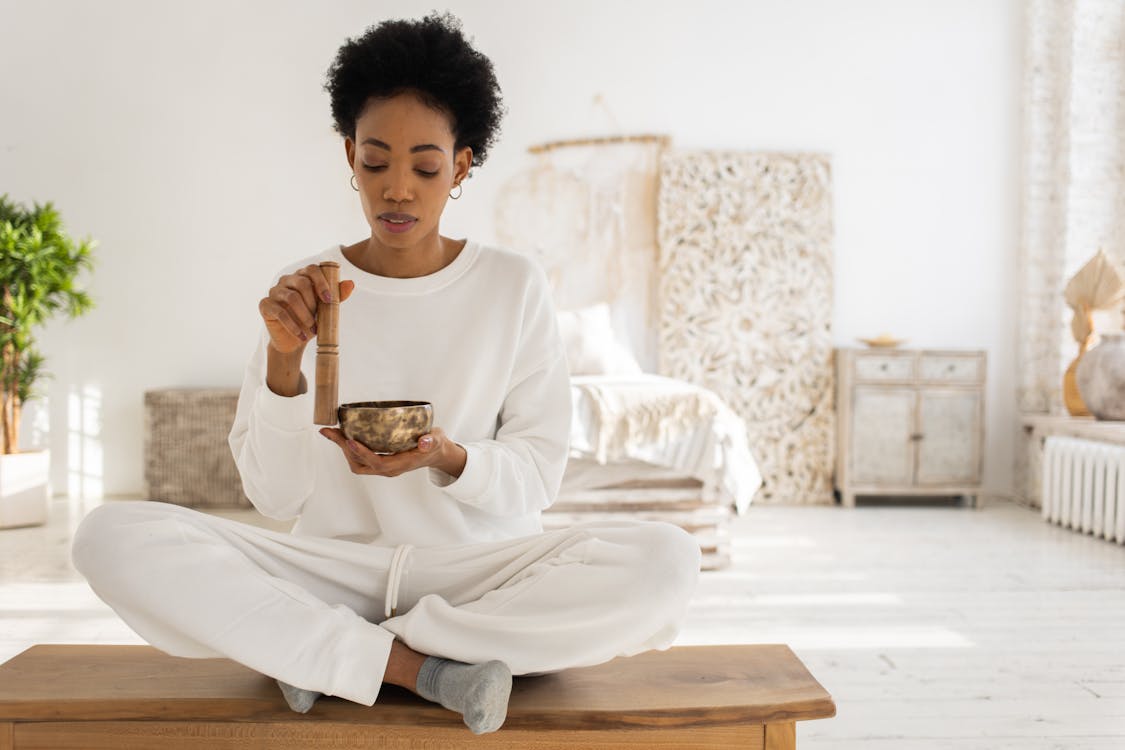 Free A Woman Using a Singing Bowl while Sitting Stock Photo