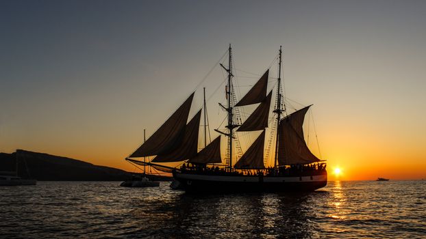 A silhouette of a classic sailing ship against a vibrant sunset over the ocean, perfect for travel themes.