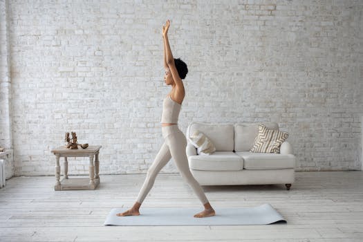 A young woman practices yoga indoors on a mat, stretching elegantly in a peaceful setting.