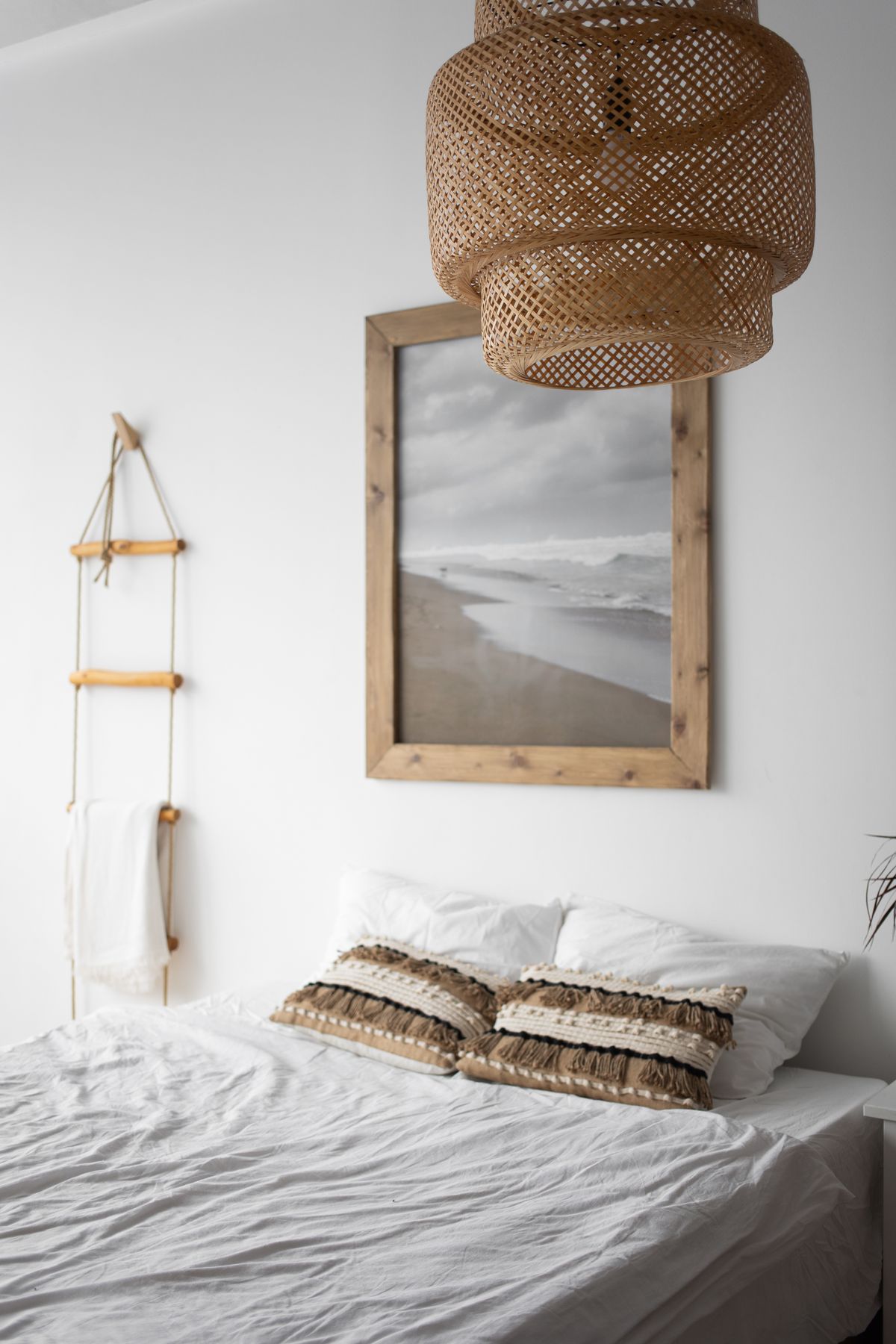 Hamptons bedroom with a rattan pendant light and coastal artwork