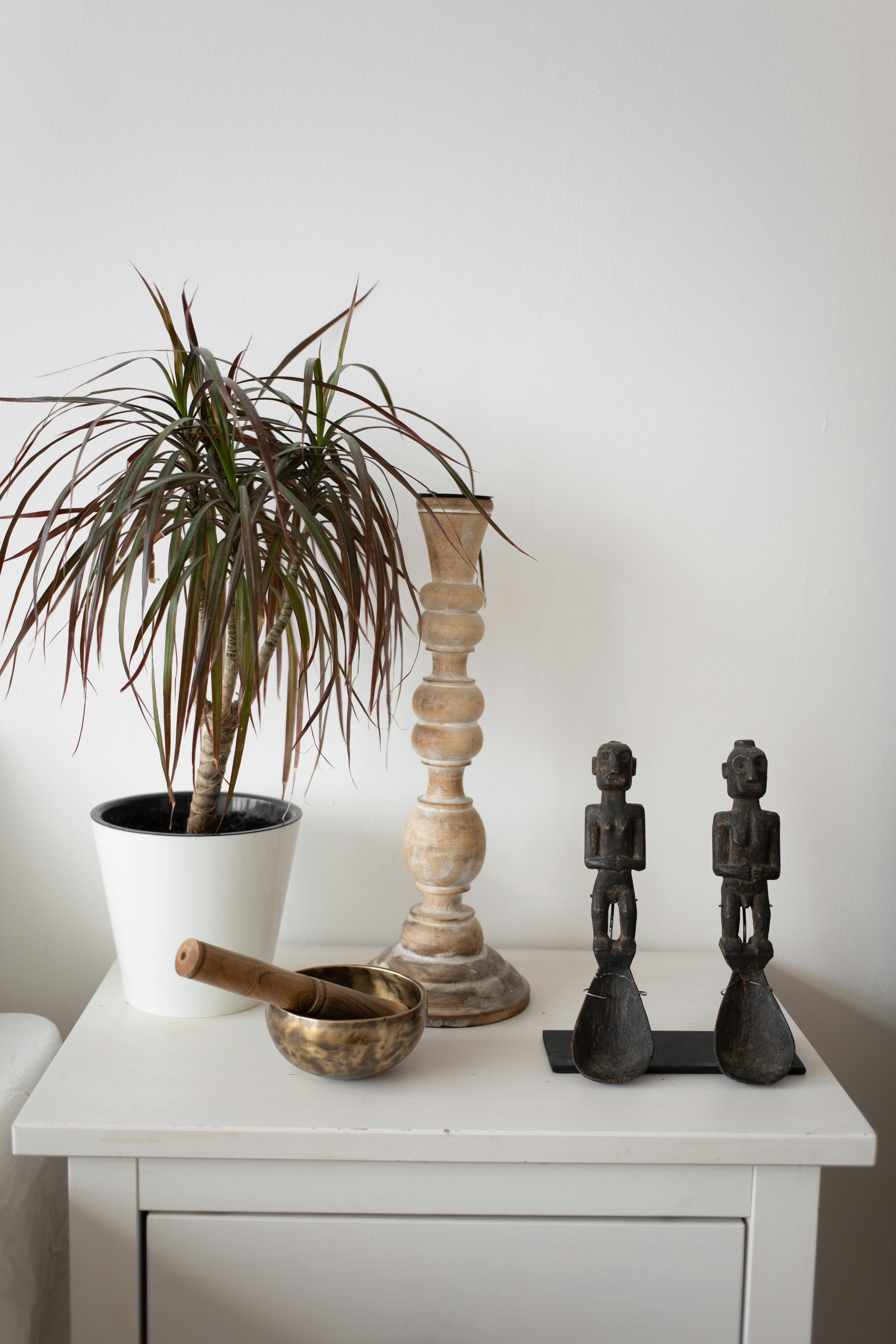 golden singing bowl candle holder potted plant and figurines on a side table