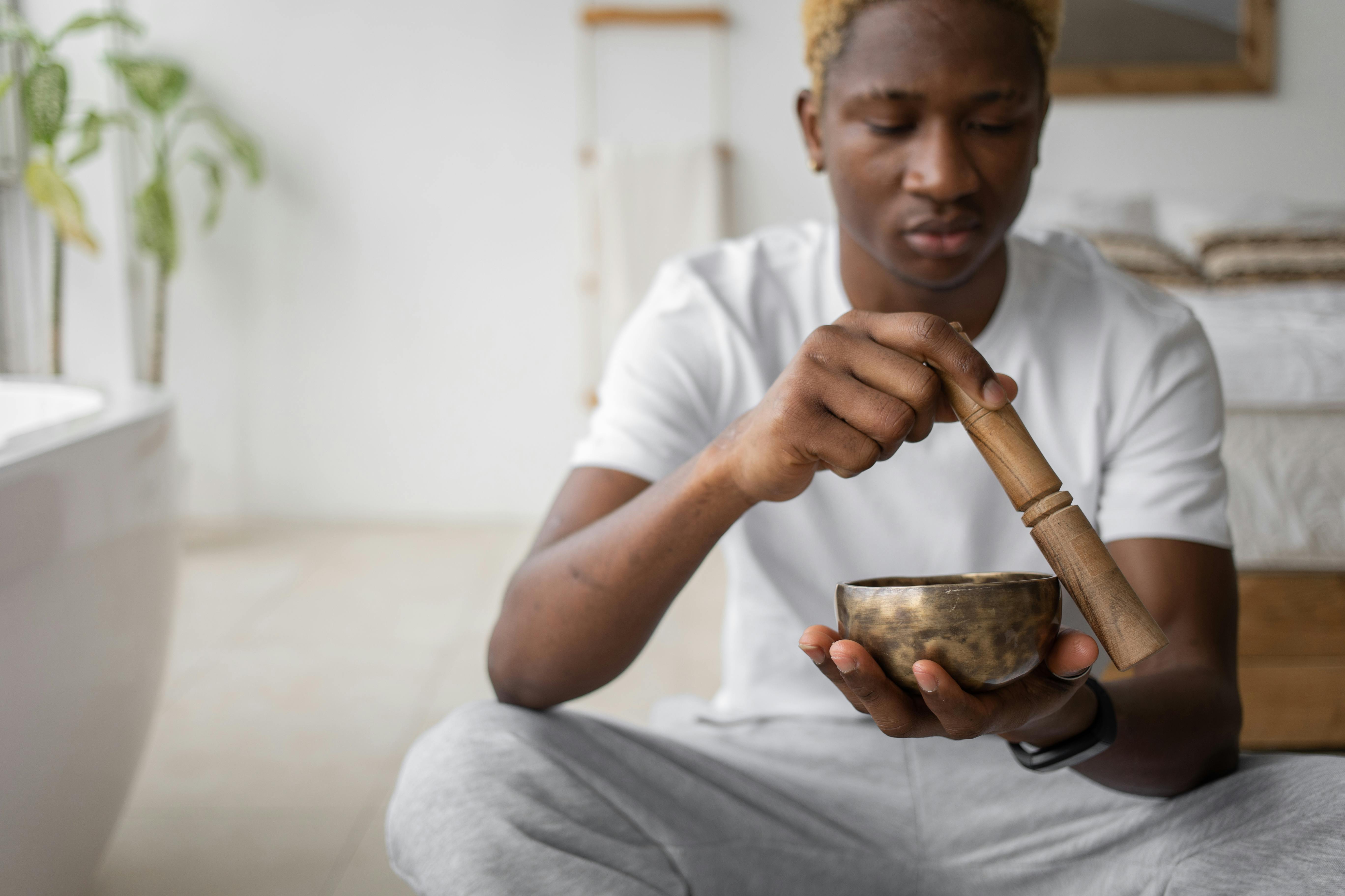 man in white shirt holding a golden singing bowl