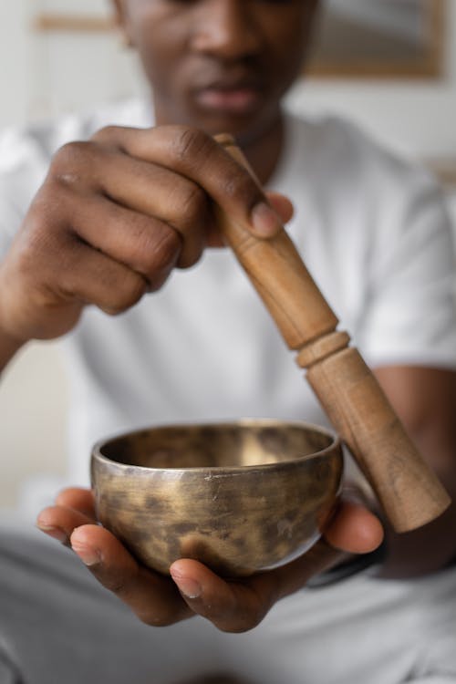 Person Holding Wooden Stick and Golden Bowl