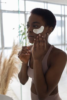 African American woman in activewear applying under eye masks as part of her skin care routine.