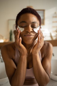 Black woman enjoying a skincare routine with under eye masks indoors.