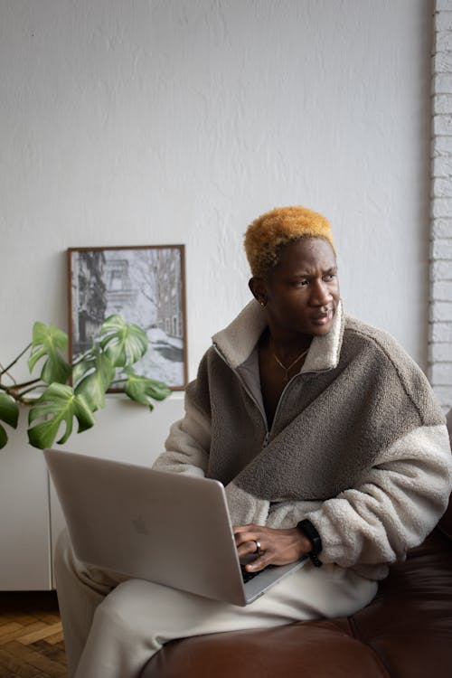 A Man in Brown Fur Coat Using a Laptop while Sitting