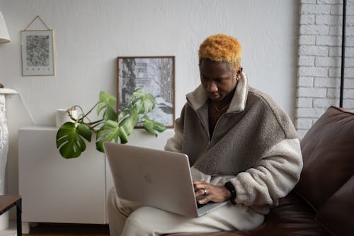 A Man in Brown Fur Coat Using a Laptop while Sitting