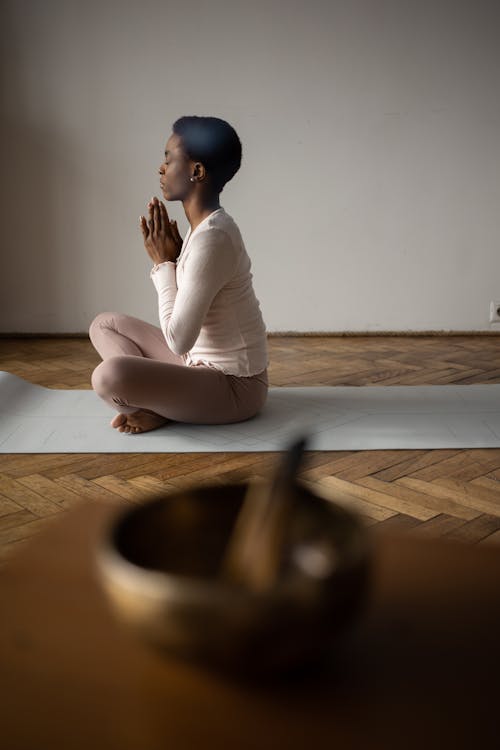 Woman Sitting Cross-legged with her Hands Clasped and Eyes Closed on a Yoga  Mat · Free Stock Photo