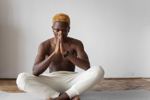 Free Peaceful meditation practice by a shirtless man in lotus position indoors. Stock Photo