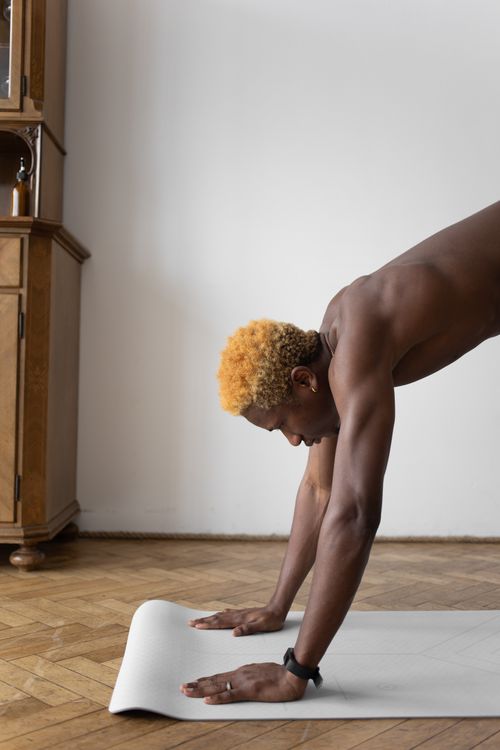 Free Man practicing yoga indoors on a mat, focusing on fitness and flexibility. Stock Photo