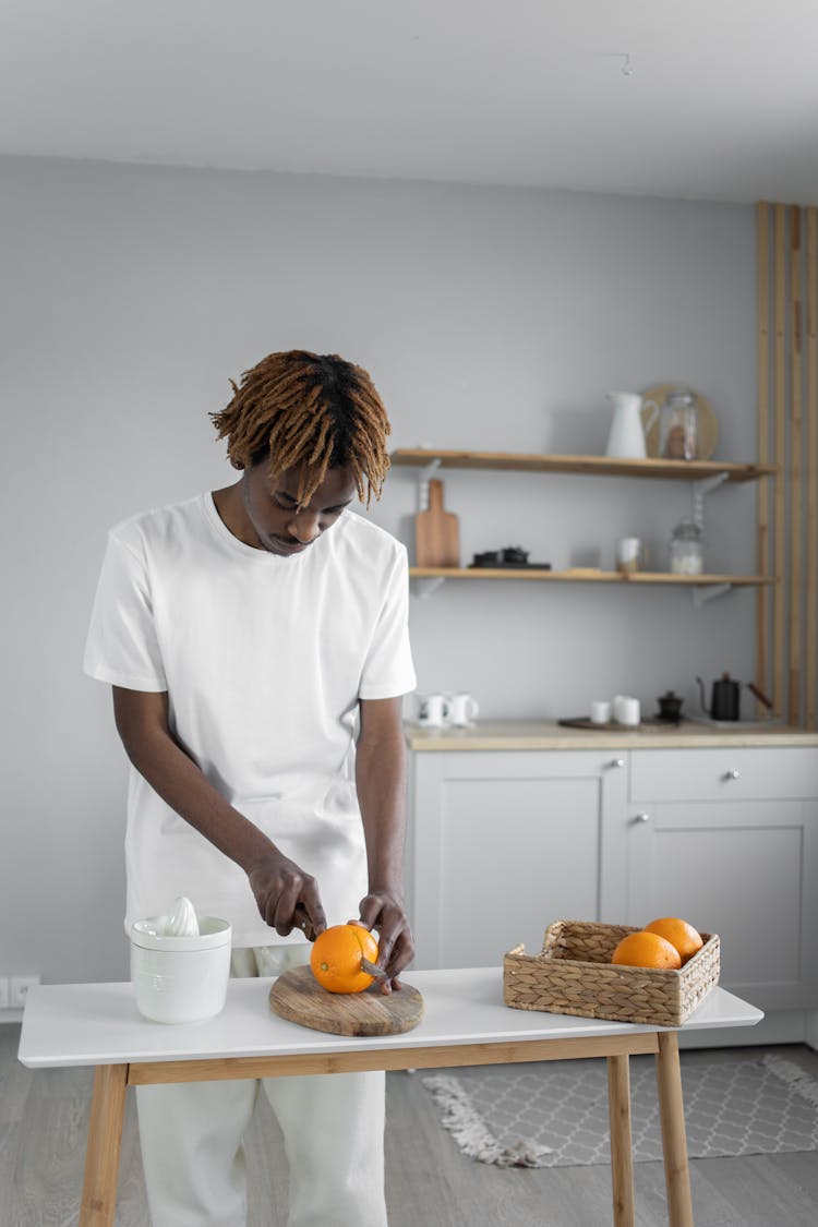 Man In White Shirt Slicing Orange On Wooden Chopping Board