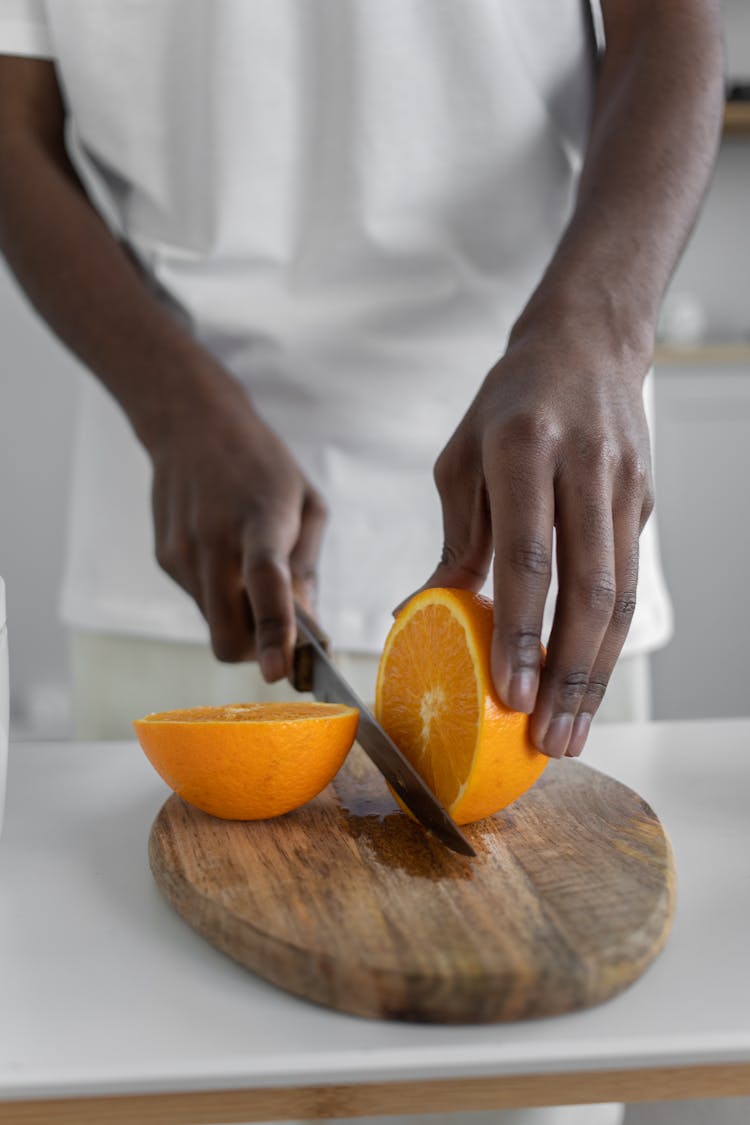 Close-Up Shot Of A Person Slicing An Orange