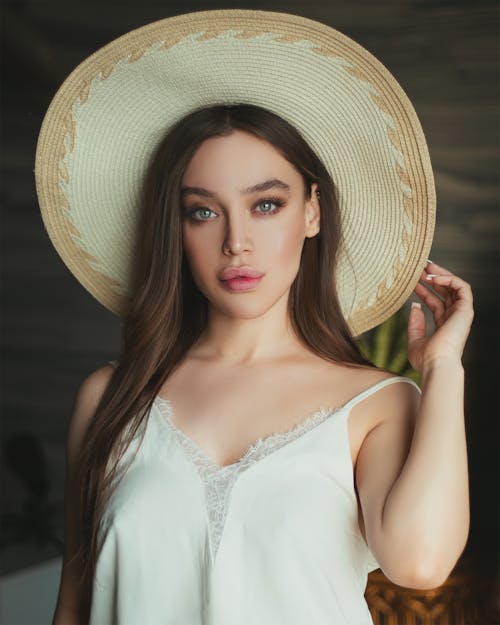 Free An Attractive Woman in White Spaghetti Strap Top Wearing a Sun Hat Stock Photo