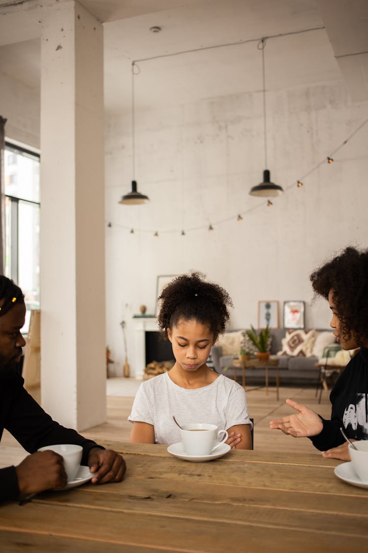 Black Mother Blaming Upset Daughter Sitting At Table Near Father