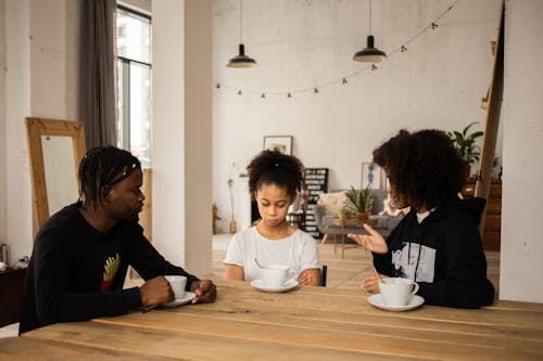 Free Black parents lecturing upset daughter at table Stock Photo