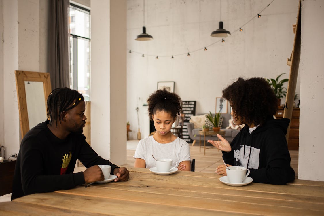 Parents lecturing upset daughter at table