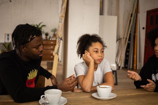Frustrated black girl between arguing parents at table