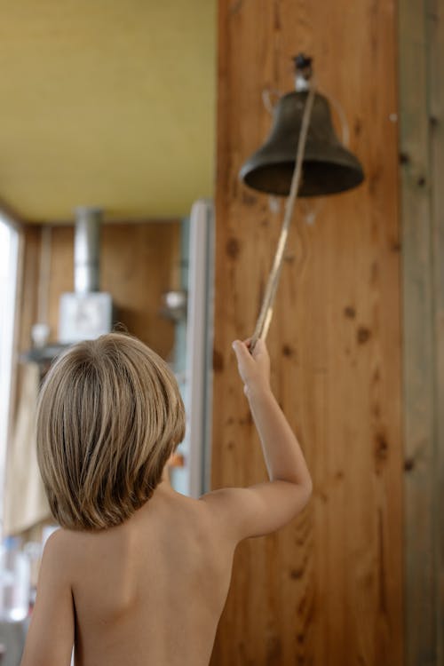 A Topless Boy Ringing a Bell