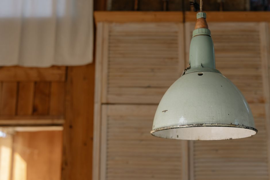 A vintage industrial ceiling lamp hanging in a rustic room with wooden elements.