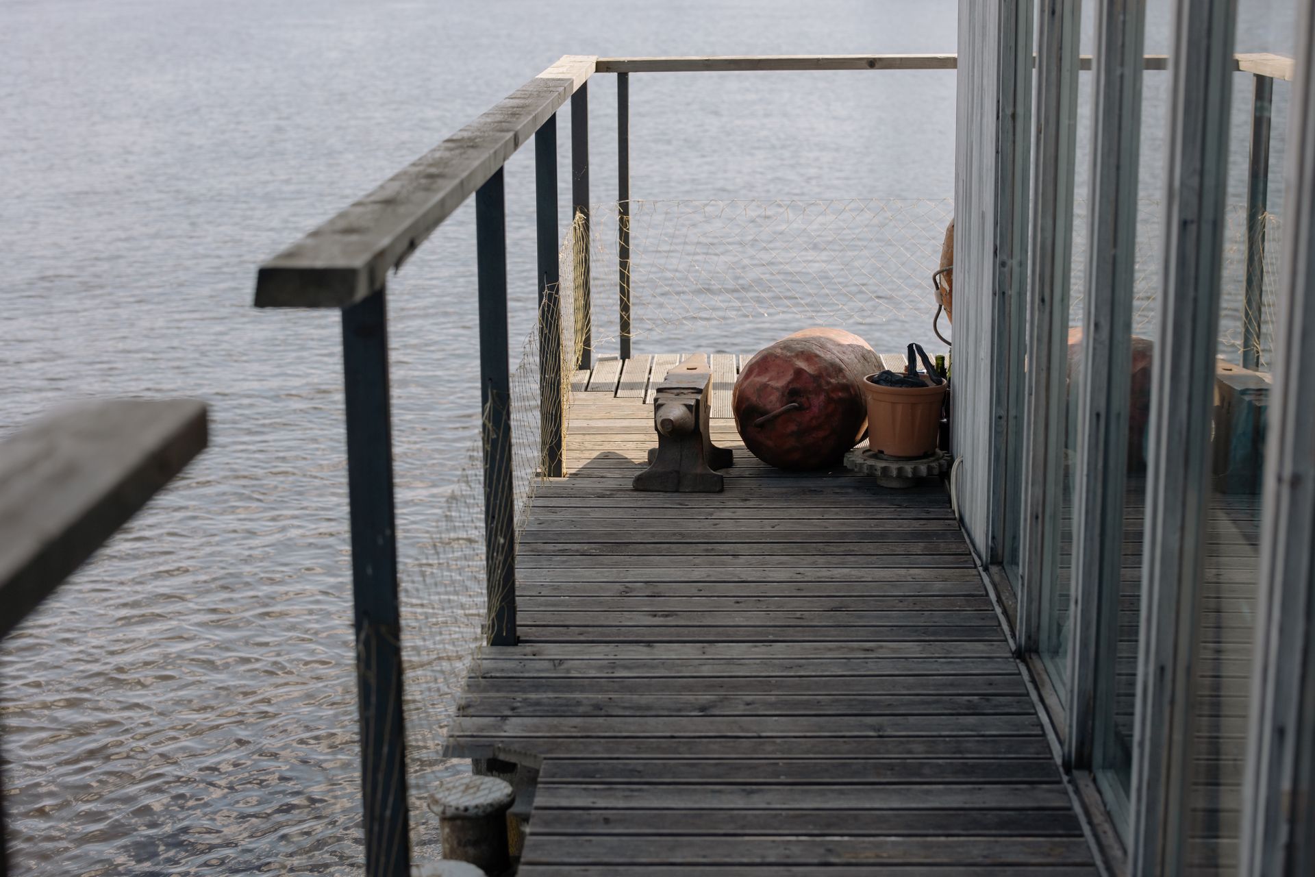 Wooden deck with seating and plants, offering a serene view over a tranquil body of water.