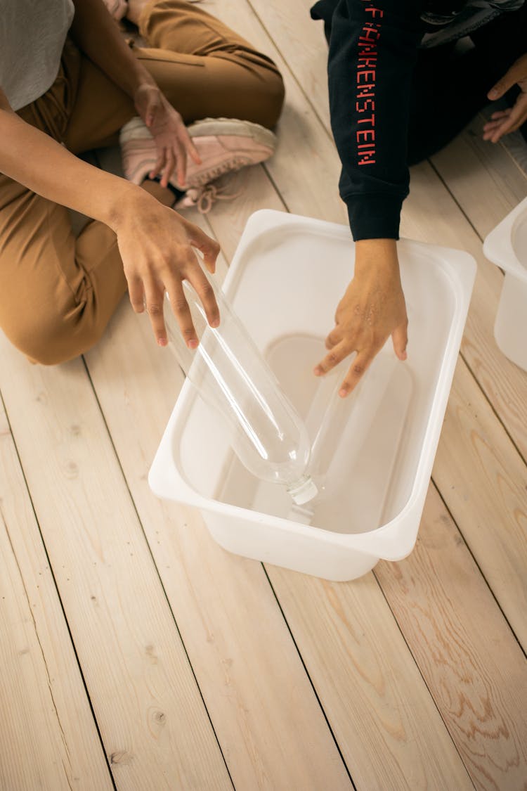 Unrecognizable People Putting Plastic Bottles In Container