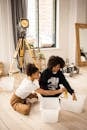 African American girls in casual clothes sitting on wooden floor while sorting banana peel into separate containers in light room