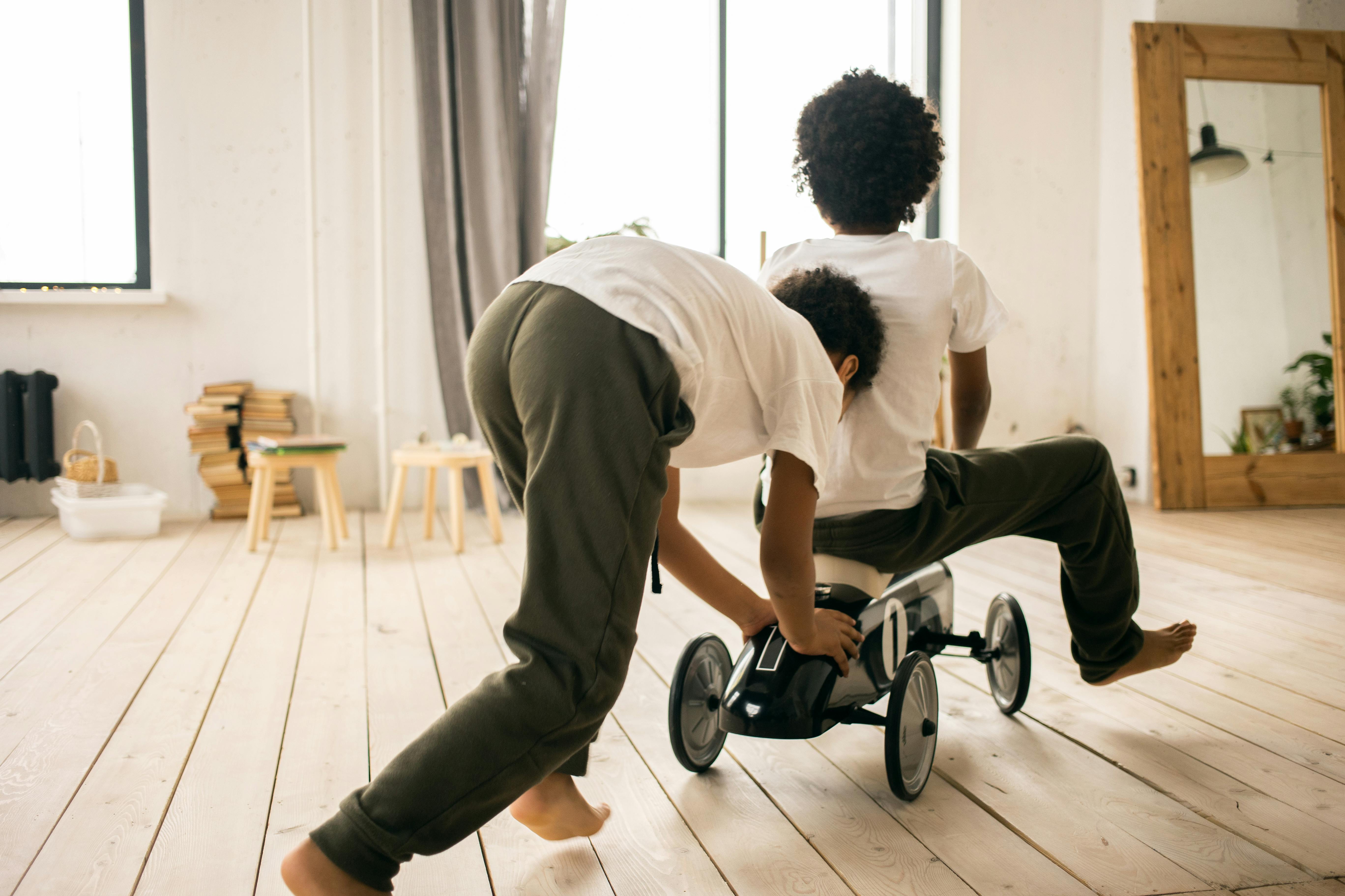 Unrecognizable black brothers riding toy car · Free Stock Photo